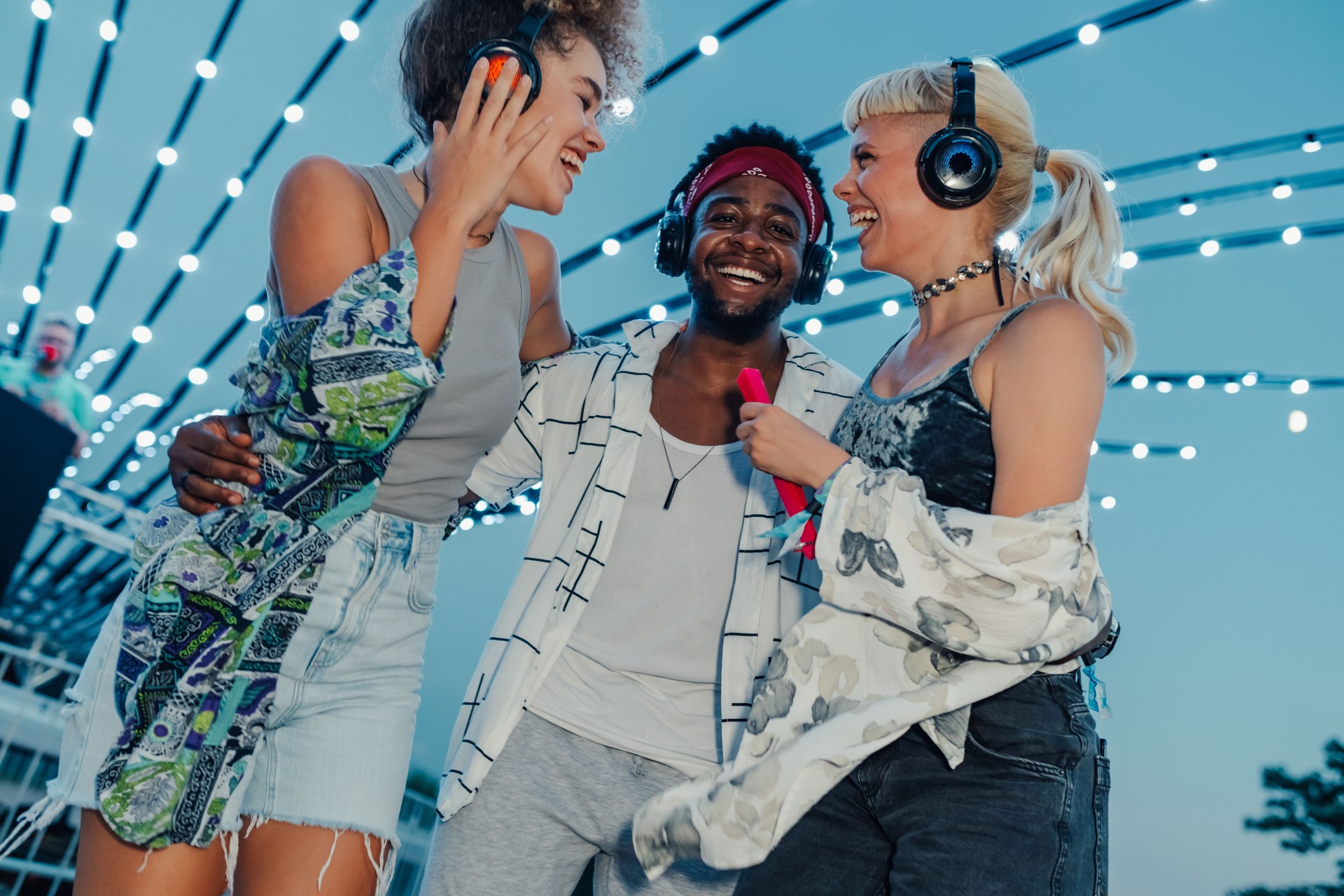 Happy friends enjoying music festival with wireless headphones